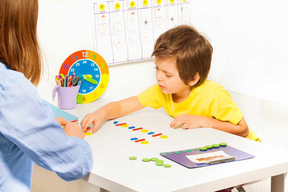 Photo d'un enfant face à une enseignante avec time timer et planning visuel