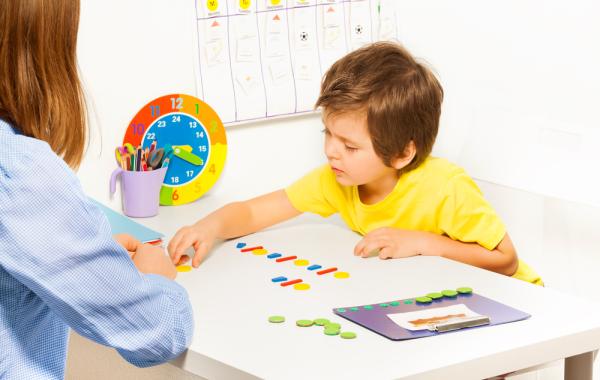 Photo d'un enfant face à une enseignante avec time timer et planning visuel